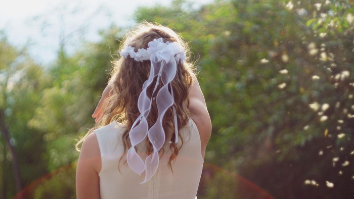 En kvinde med hårbånd og lang hår står i en trækirkegård