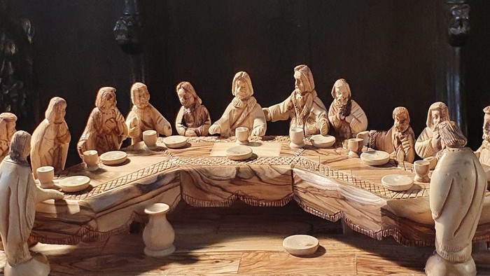 Komplexe Holzschnitzerei, die das Abendmahl mit detaillierten Figuren und Tischarrangement darstellt.