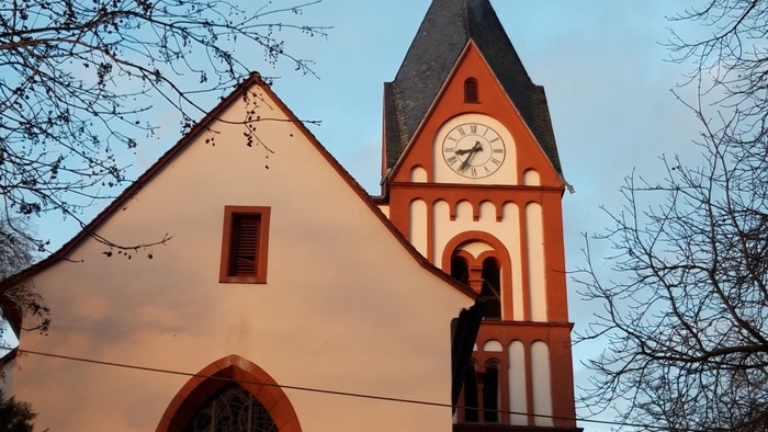 Weißer Kirchturm mit Uhr und spitzem Dach bei Tageslicht