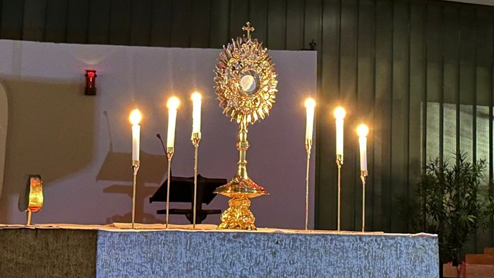 Innenraum einer Kirche mit Altarraum, Kerzen und Blumen