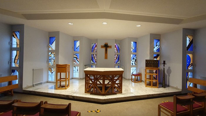 Die Kirche mit Altar, Stühlen und farbenfrohen Fenstern