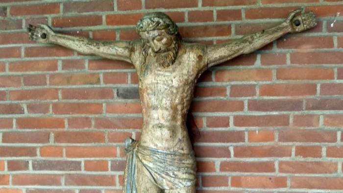 Bronzene Kruzifix-Statue von Jesus Christus, befestigt an einer Ziegelwand.