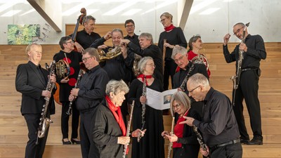 En gruppe musikere i formelt tøj, der holder forskellige træblæseinstrumenter på en trætrappe.
