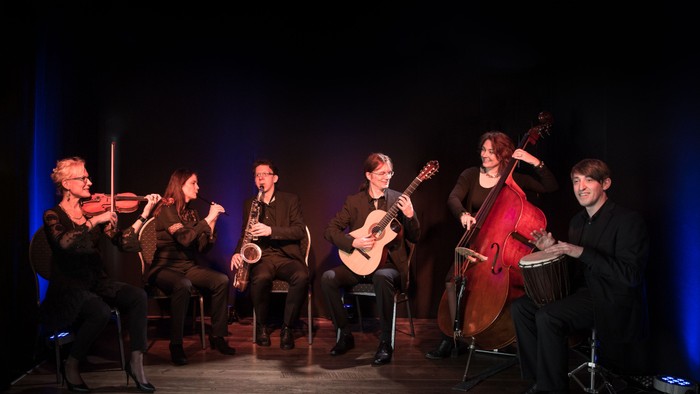 Ein Kammerensemble spielt klassische Musik mit Violinen, Cello, Gitarre und Klarinette auf der Bühne.
