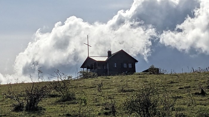 Ein einsames Haus thront auf einem Hügel unter dramatischen, wogenden Sturmwolken.