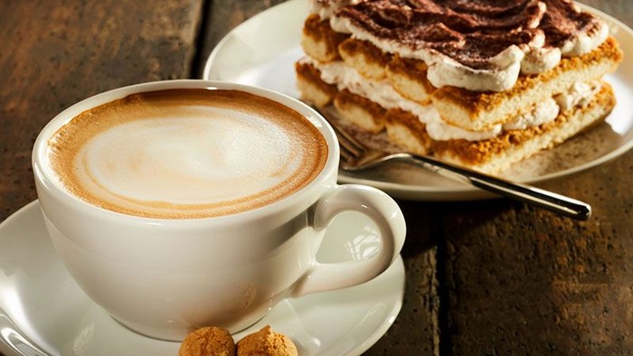 Ein Cappuccino und ein Stück Tiramisu auf einem Holztisch