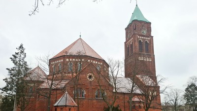 Beeindruckende Backsteinkirche mit hohem Uhrturm und einer runden Kuppel mit bunten Glasfenstern.