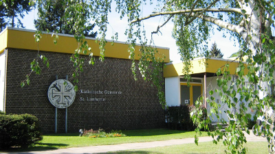 Das Bild zeigt ein Gebäude der Katholischen Universität St. Georgen mit einem gelben Dach und einem Baum davor.
