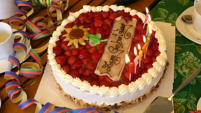 Ein Geburtstagskuchen mit Erdbeeren und Kerzen auf einem Tisch.