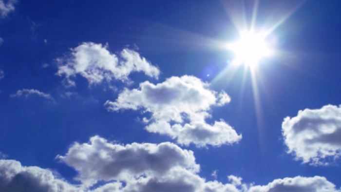 En klar blå himmel med flåde af hvide skyer og solskin.