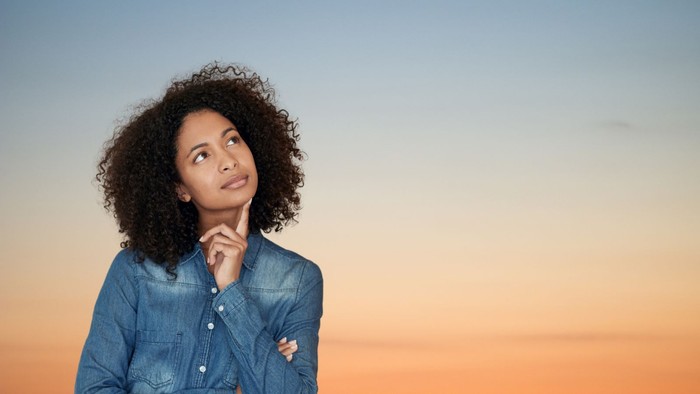 Junge Frau mit schwarzen Locken, die zweifelnd nach oben schaut