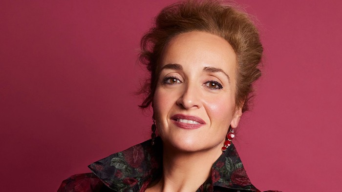 Alexandra Sherman vor einem dunkelroten Hintergrund im Abendkleid