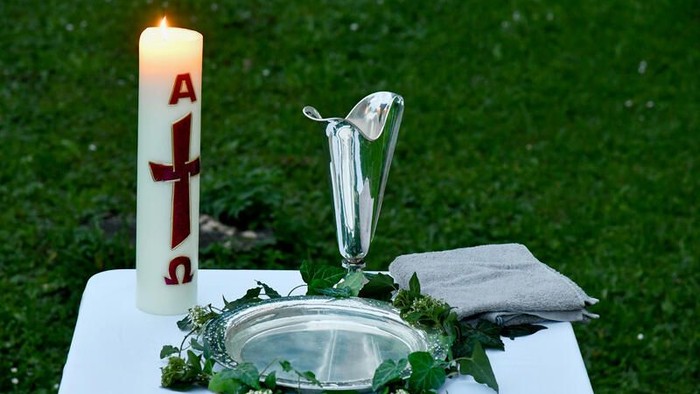 Eleganter Outdoor-Altar mit einer Kerze, einem silbernen Kelch und einem mit Blumen geschmückten Becken mit einem Handtuch.