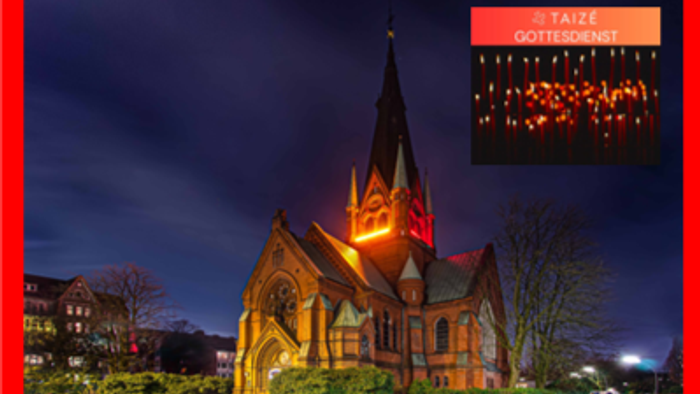 Bild zeigt eine beleuchtete Kirche bei Nacht mit einem Weihnachtsfenster.