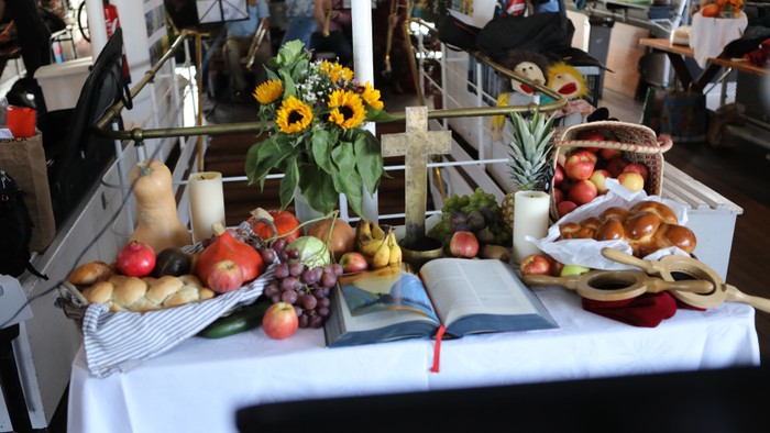 Ein Tisch mit Obst, Gemüse und Blumen, umgeben von Menschen und Fahrrädern