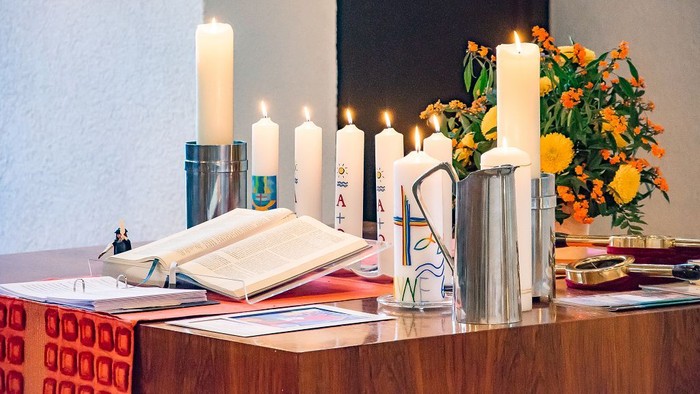 Altar mit Kerzen, Blumen und religiösen Büchern