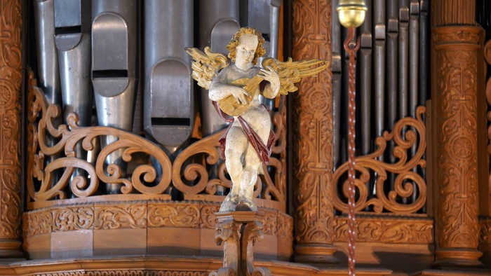 Engelstatue vor einem Holzorgelpfeiler