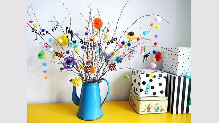 En blå vase med farvede blomsterstænger og to pakker på en gul flade