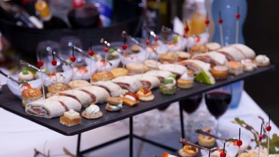 Elegant udvalg af lækre fingerfood og mini-sandwiches på etagerede fade med dekorative tandstikker.