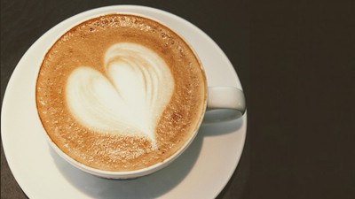 En kaffe med hjerteformet skum på en hvid underduk.