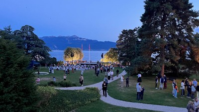 Folk samles ved en smuk søpark i tusmørket og nyder en udendørs begivenhed ved vandet.