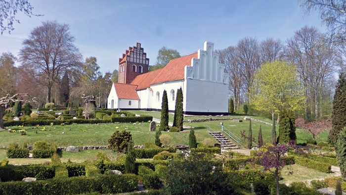 En smuk kirke med omgivelser af grønne planter og træer