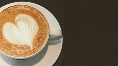 En kaffe med hjerteformet skum på en hvid underduk.