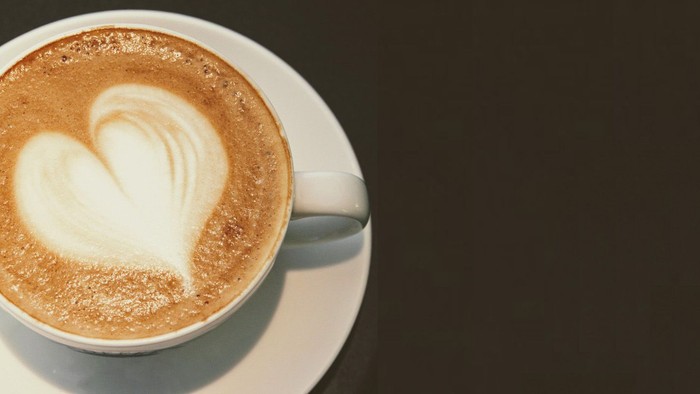 En kaffe med hjerteformet skum på en hvid underduk.