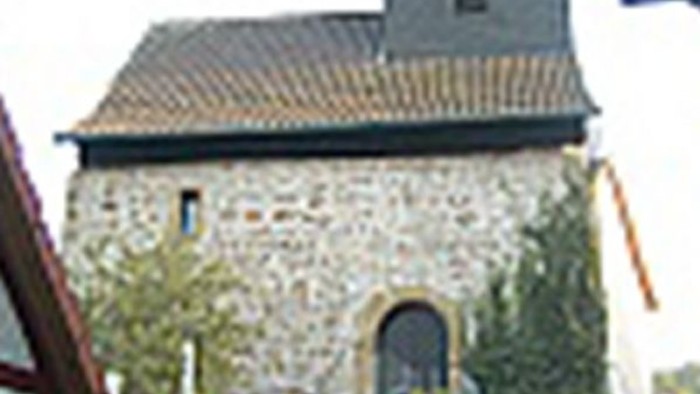 Kleines Steingebäude mit Rundbogentür und kleinem Turm.