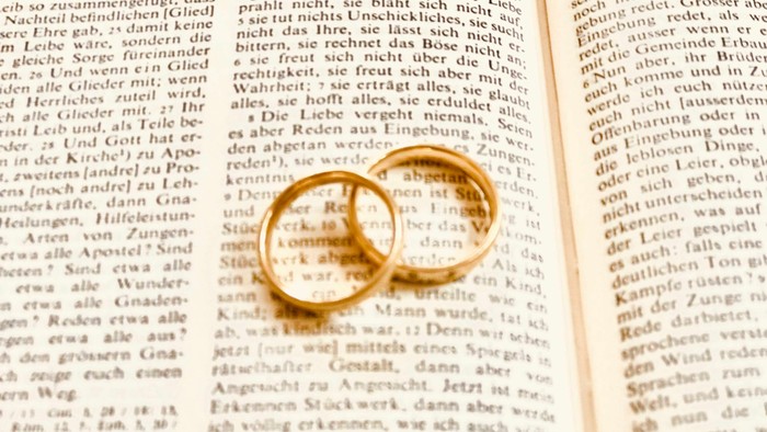 zwei Eheringe liegen auf geöffneter Bibel