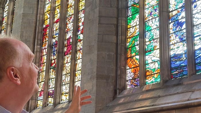 Man admiring colorful stained glass windows in a church.