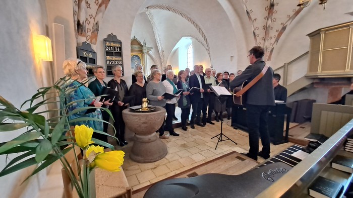 En kor sang i en kirke med blomster og lys.