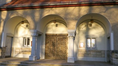 Das Bild zeigt einen prächtigen Eingang mit drei Bögen und einer verzierten goldenen Tür.