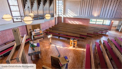 Modernes Kircheninnere mit Holzpulten und großen Fenstern