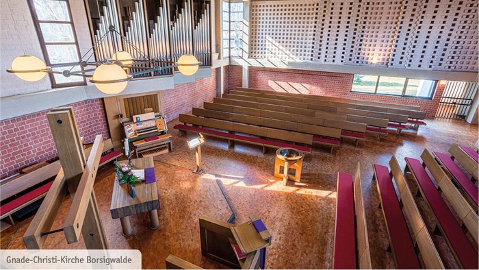 Modernes Kircheninnere mit Holzpulten und großen Fenstern