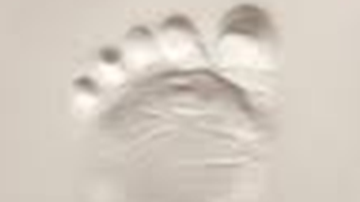 Et svagt aftryk af et lille barns bare fod på en lys overflade.