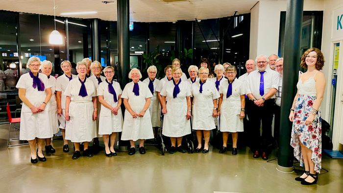 En gruppe ældre personer i uniformer og binder poserer til et billede