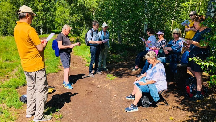 En gruppe af turister hører en guide tale i skoven