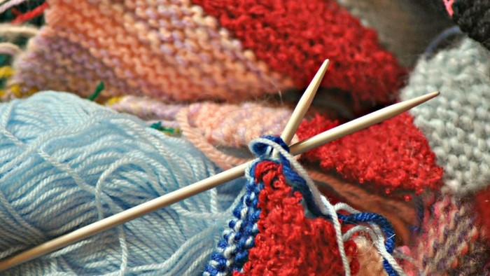 Mehrere Stränge Wolle in verschiedenen Farben und Knäuel auf Nadelspitzen