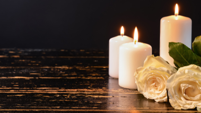 Zwei brennende Kerzen und weiße Rosen auf dunklem Holztisch