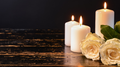 Zwei brennende Kerzen und weiße Rosen auf dunklem Holztisch