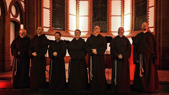 Mönche in traditionellen Roben posieren gemeinsam in einer prächtigen, schwach beleuchteten Kirche.