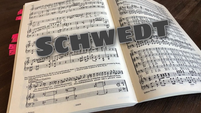 Geöffnetes Notenbuch mit der Aufschrift „Schwedt“ und musikalischen Notationen auf den Seiten.