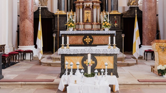 Aufwendiger barocker Altar mit einer Kreuzigungsskulptur, prunkvollen Goldverzierungen und Statuen in einem prächtigen Kircheninnenraum.