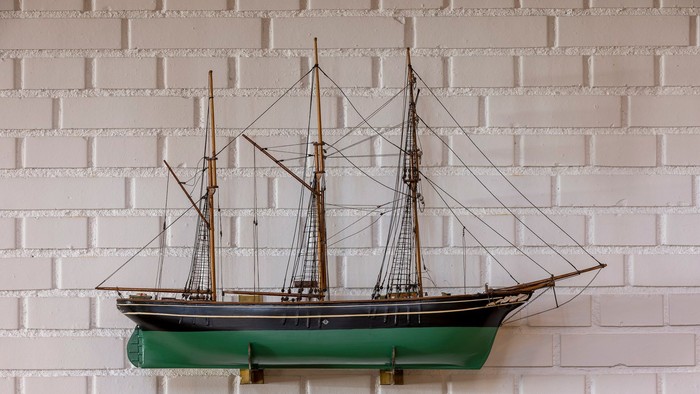 Et smukkt modelleret skib monteret på en hvid mursten.