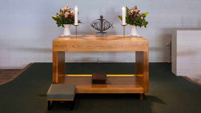 En moderne kirkeinteriør med alter, lys og blomster.