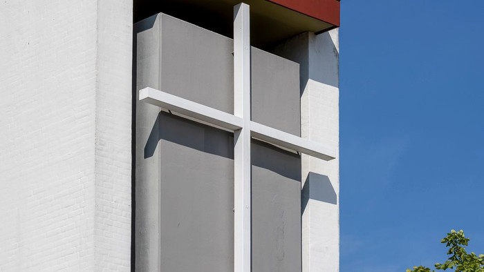 Hvide kors på hvide væg med træ i baggrunden