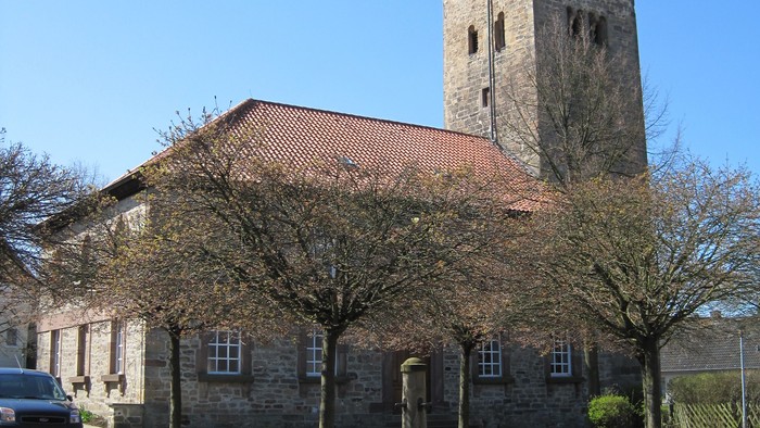 Außenansicht der evangelischen Kirche in Ehlen. Natursteingebäude mit rotem Ziegeldach und hohem Turm.