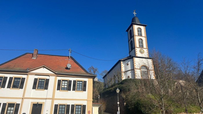Weißes Gebäude mit roter Ziegeldach und hoher Uhrenturm