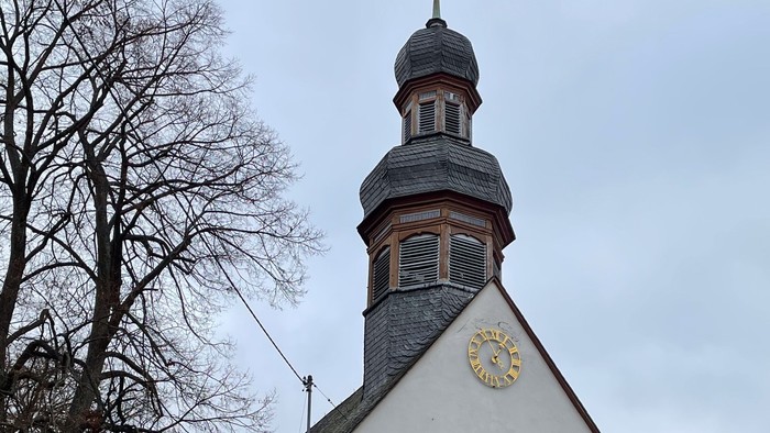 Weiße Kirche mit hohem Turm und Uhr.
